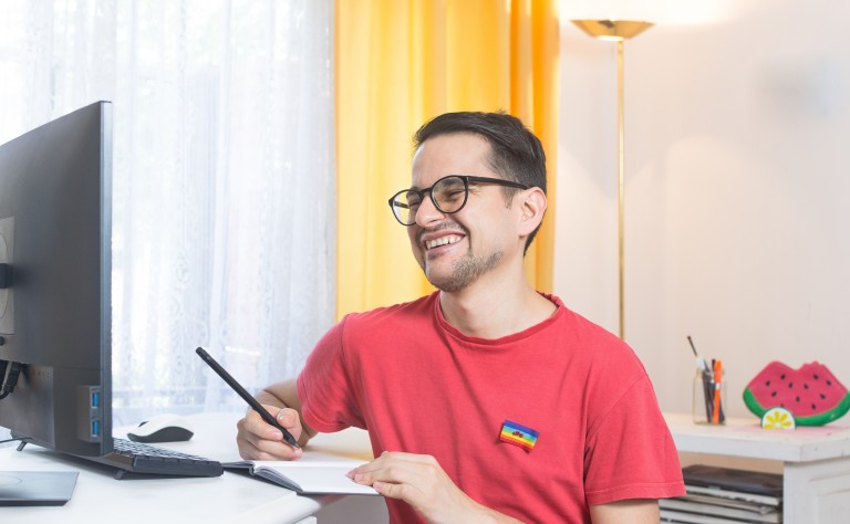 Young Man wearing red t-shirt smiling at computer